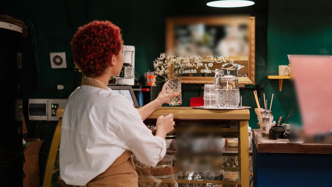 カフェのショーケースの前で、棚を整える店主の後ろ姿